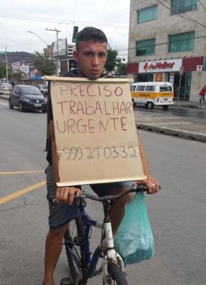 De bicicleta e com cartaz, jovem percorre a cidade pedindo emprego